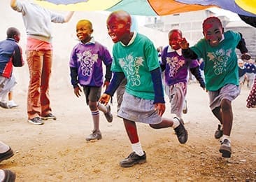 Kenyan children run beneath a parachute during a VBS conducted by a mission team from Crossroads Christian Church, Corona, California. Photo Â©Gabi Adams.