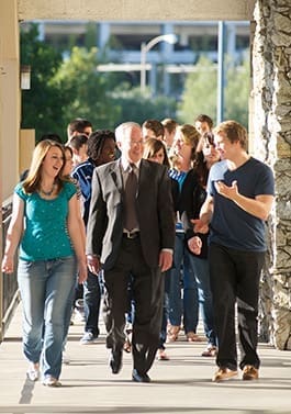 Hope International University President John Derry walks across campus with students.