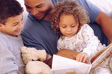 Father reading story to daughter and son